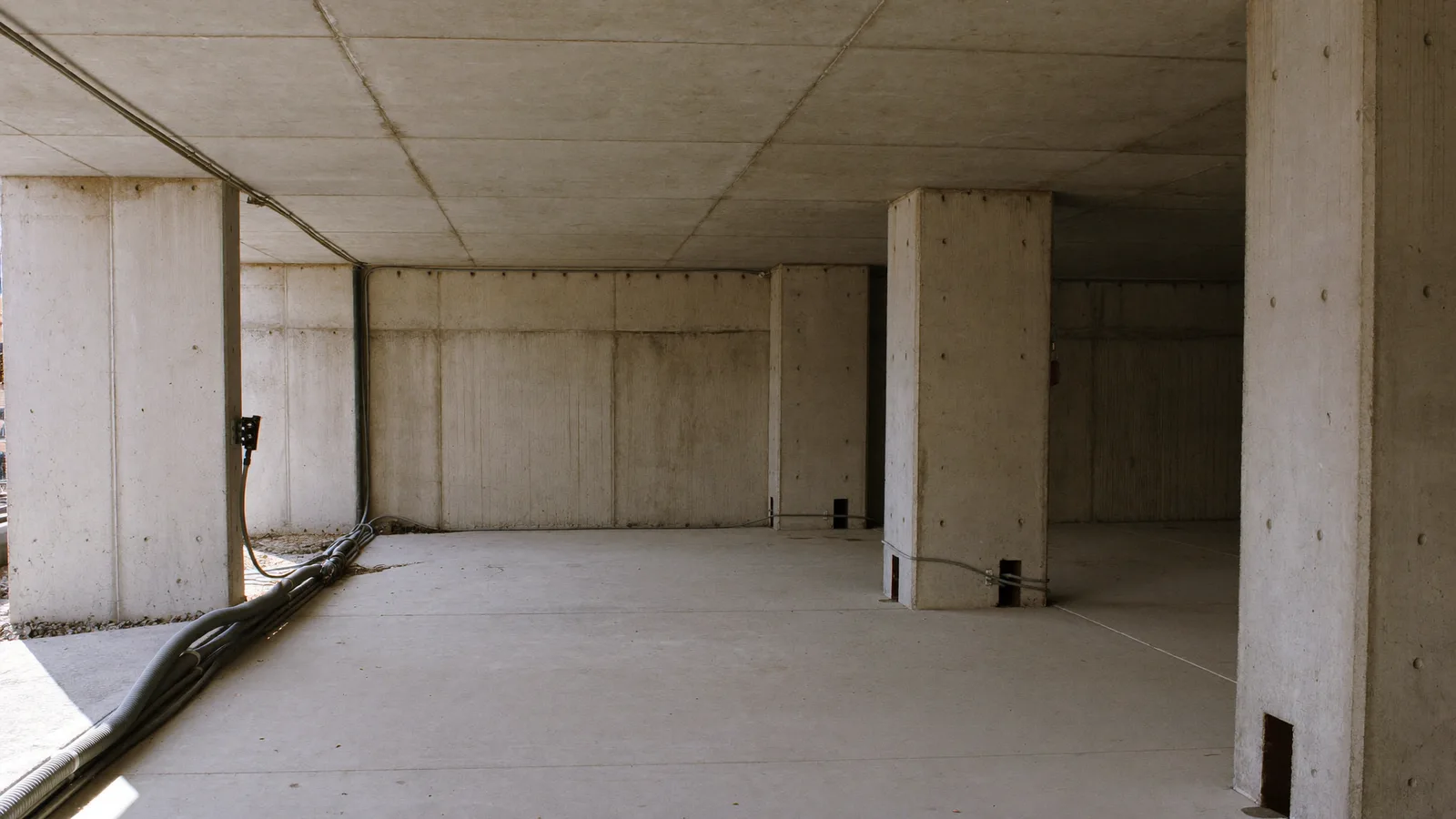 Bare concrete deck of a parking structure under construction, with conduit run and stubbed up through the slab