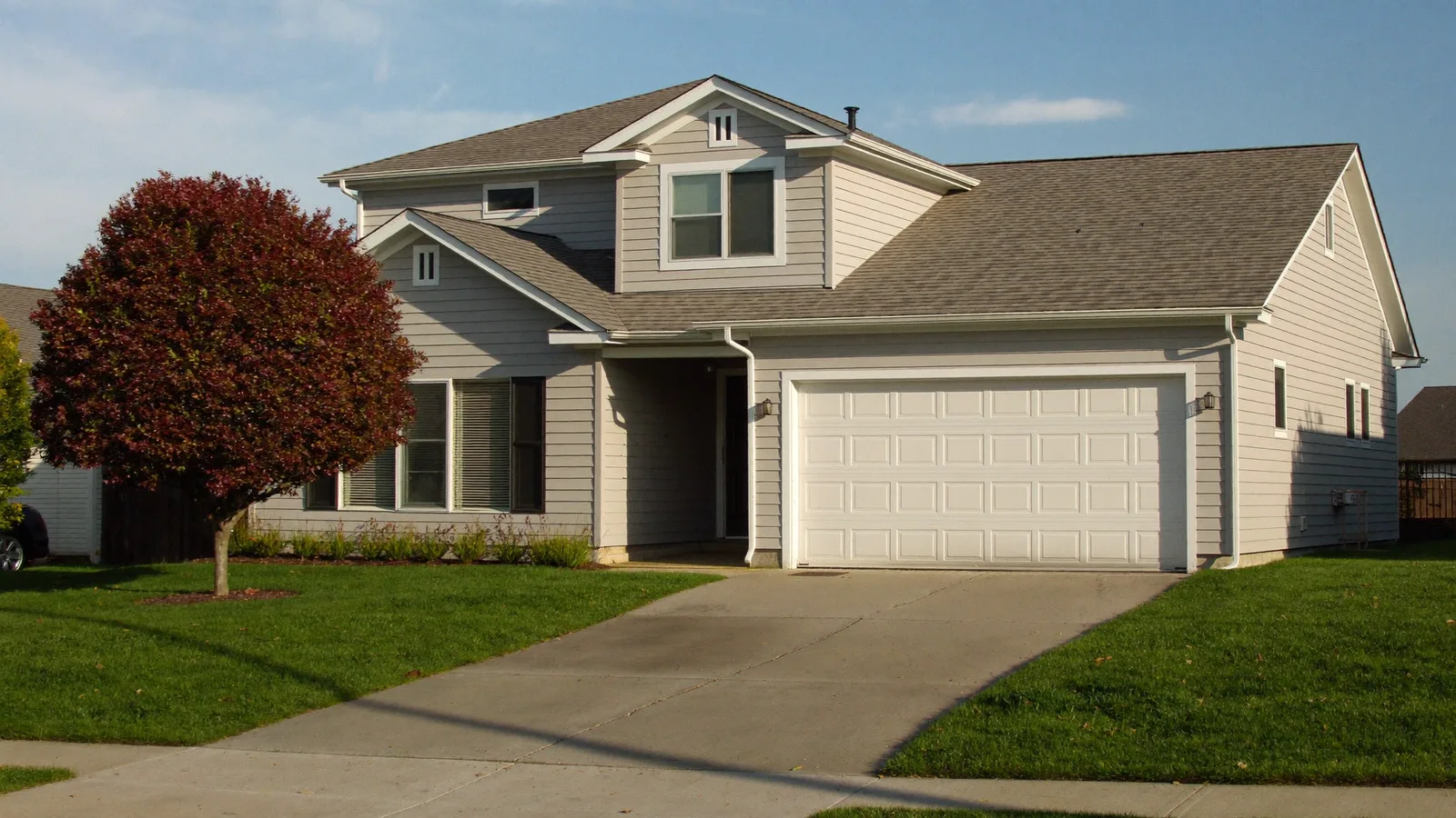 A two-story suburban American house with an attached two-car garage and concrete driveway